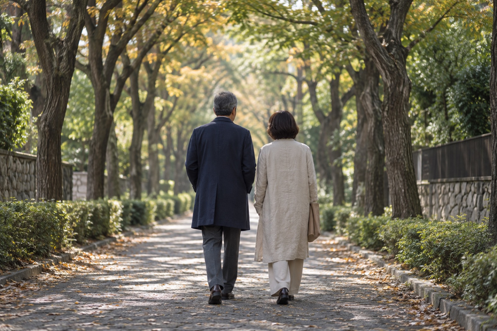 秋の並木道を並んで歩く、大人の男女の後ろ姿